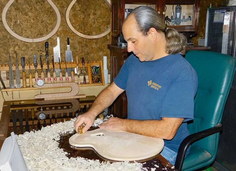 Luthier Erich Solomon works on an acoustic guitar back piece
